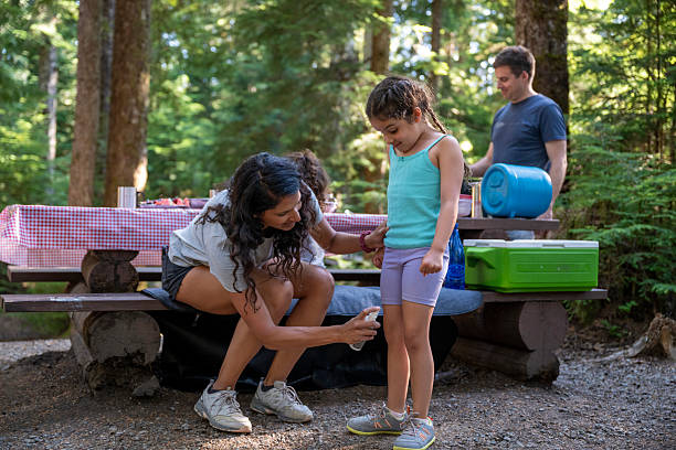 mother sprays young daughters with bug repellent at campsite in forest, b.c. mother sprays young daughters with bug repellent at campsite in forest, b.c.